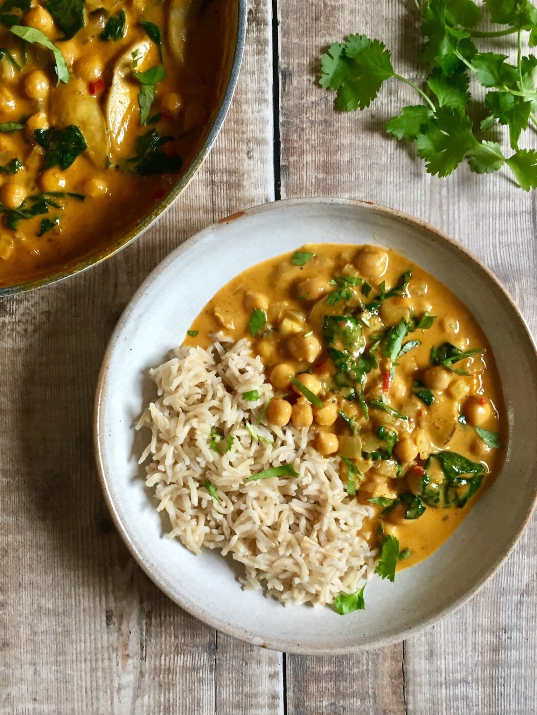 Curry de pois chiches, champignons et épinards avec du riz et de la coriandre saupoudrés sur le dessus.
